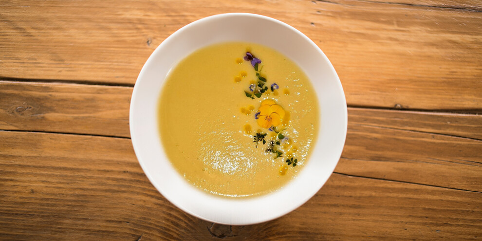 Suppe mit goldenem Apfel und Blumen